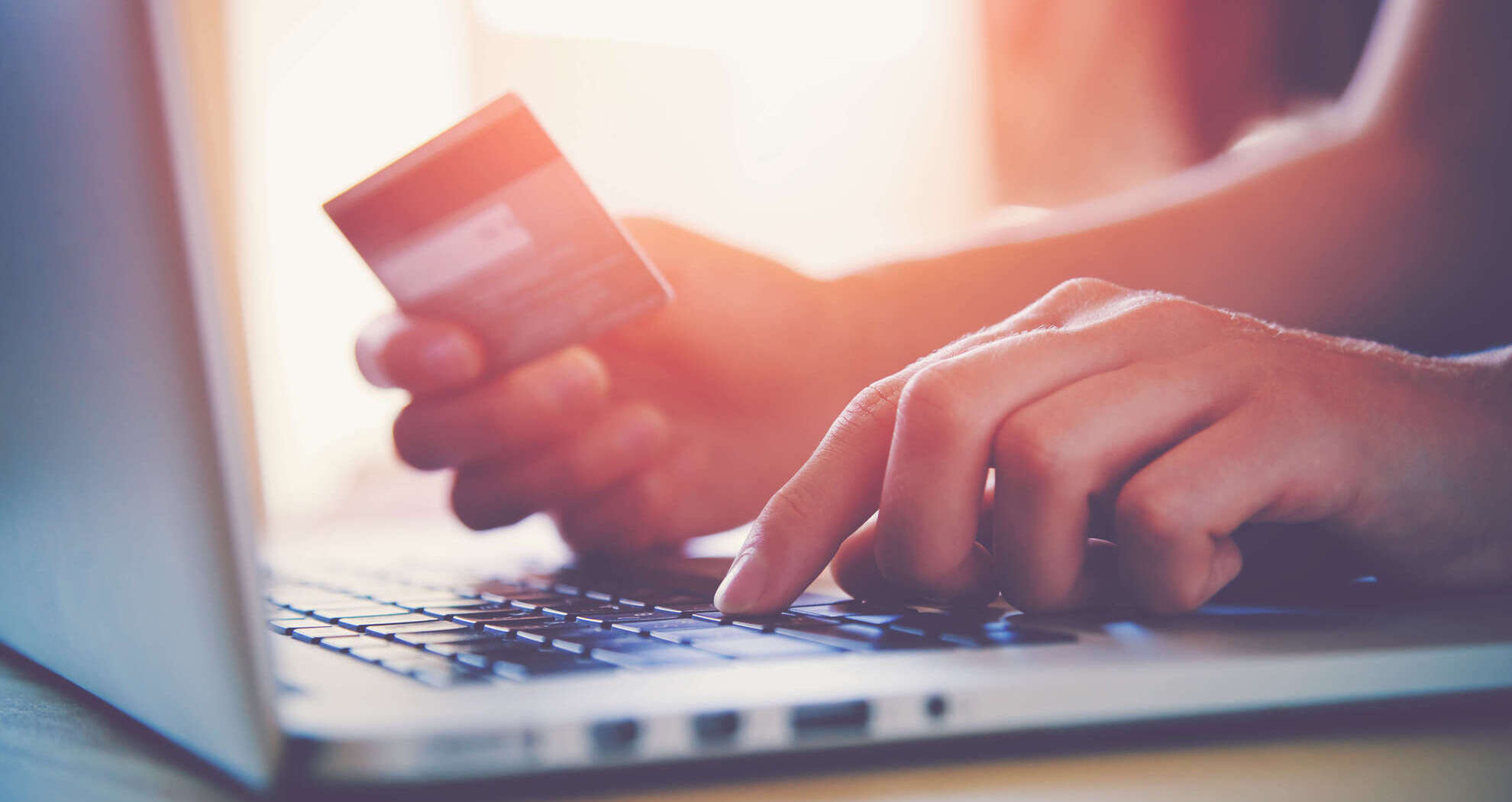 Person holding a bank card while using their laptop.