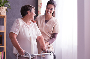 Nurse helping elderly woman on walking frame