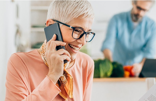 Woman in her kitchen ringing AIB to learn about opening an account.