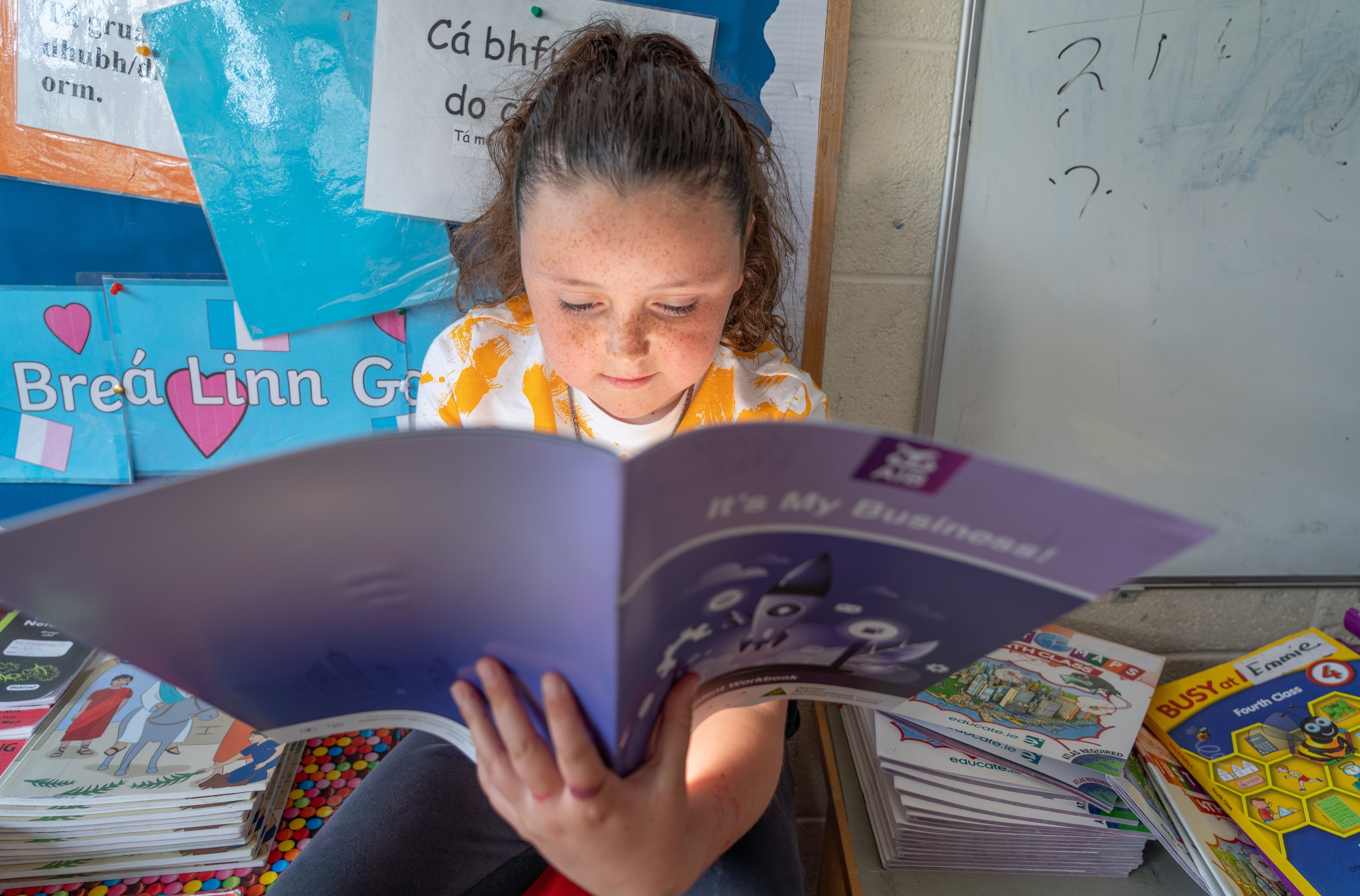 A young girl reading about the AIB 'it's my business' programme.